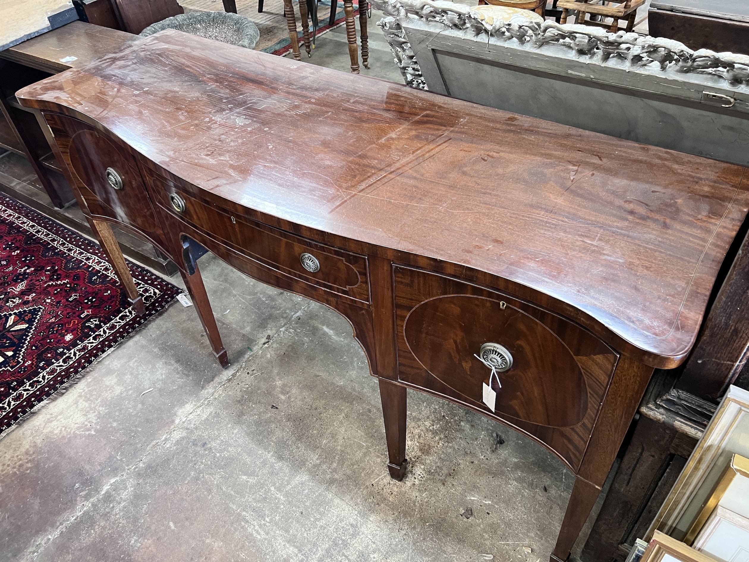 A George III style mahogany serpentine sideboard on square tapered legs, width 184cm, depth 63cm, height 93cm